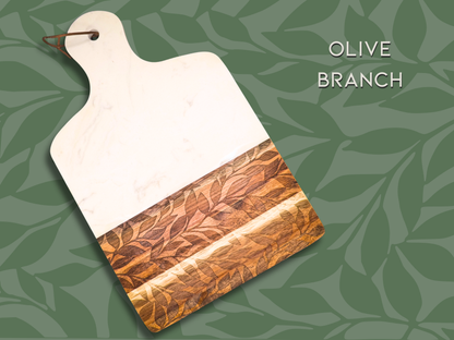 A marble and wooden charcuterie board engraved in the pattern "olive branch". This is an organic pattern that resembles silhouetted branches of an olive tree.