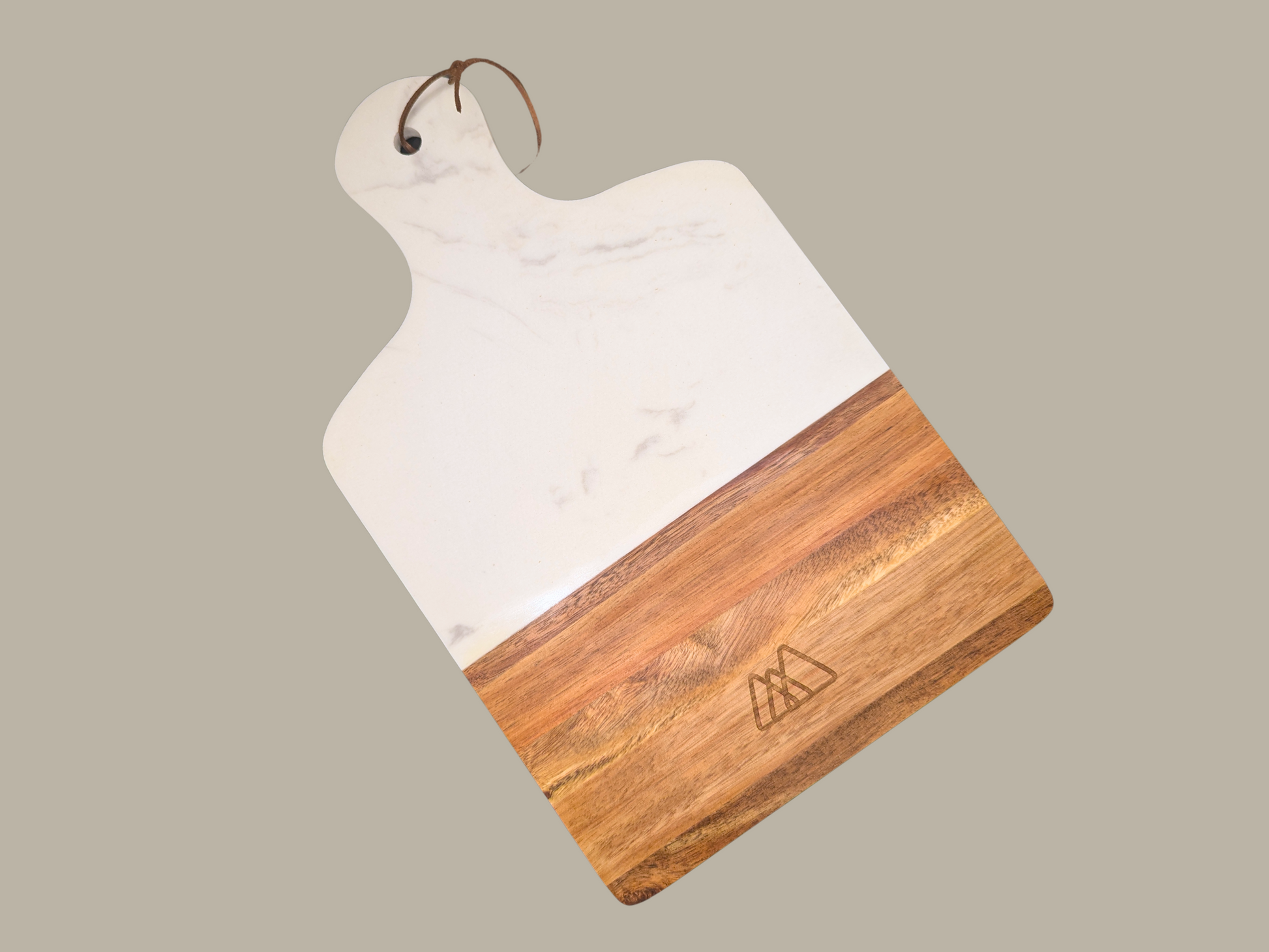 A marble and wood serving tray engraved with the Three Spruce Studios logo, three overlapping rounded triangles