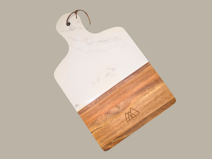 A marble and wood serving tray engraved with the Three Spruce Studios logo, three overlapping rounded triangles